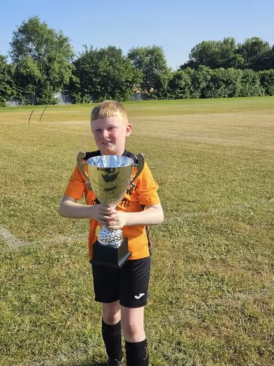 A young Hebburn Sparks player holding the Beacon of Light Trophy