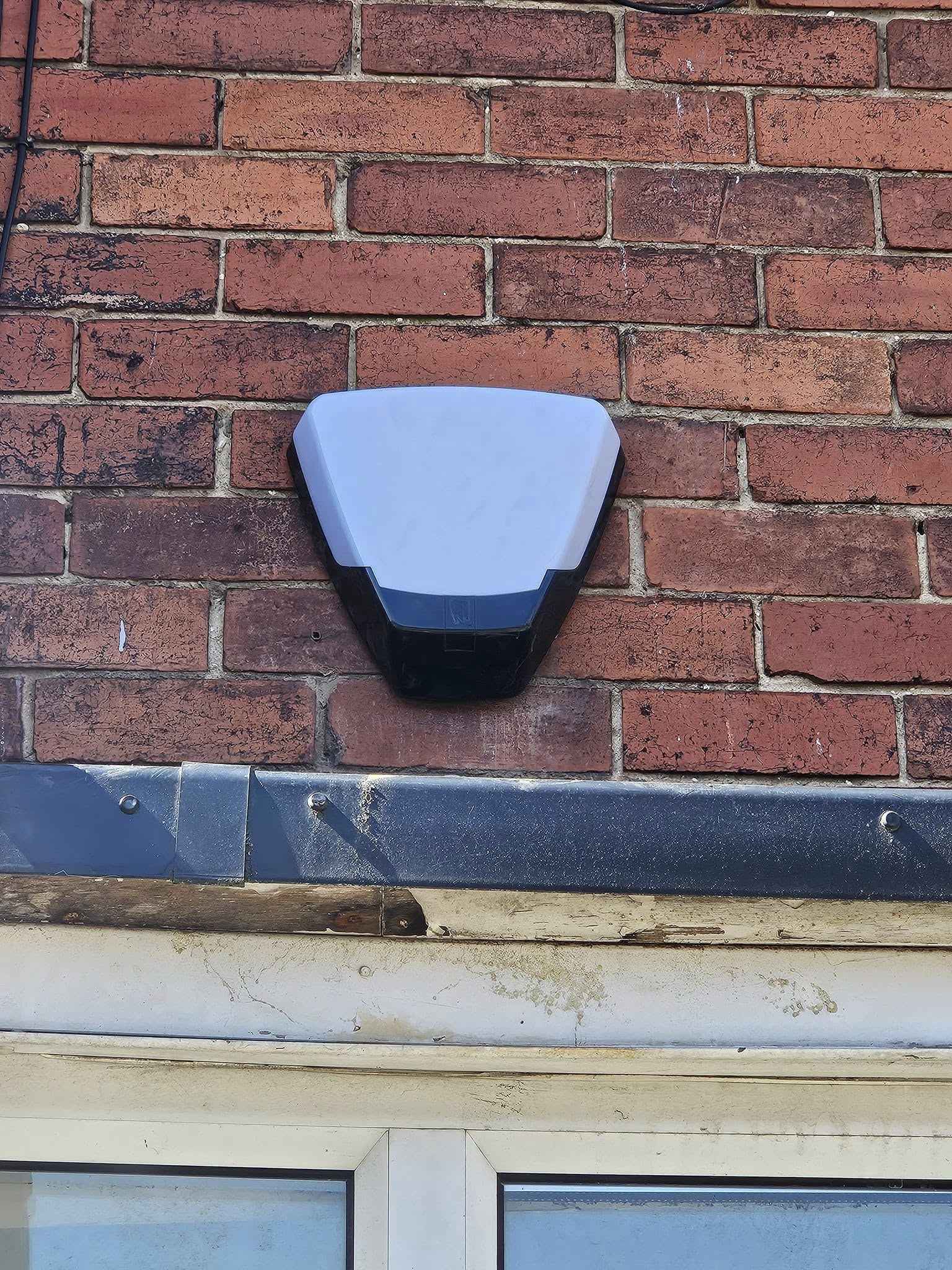 An external alarm bell box and siren fitted to a brick wall