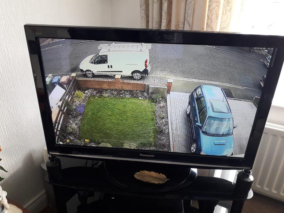 A live CCTV feed shown on a TV, covering the garden and street
